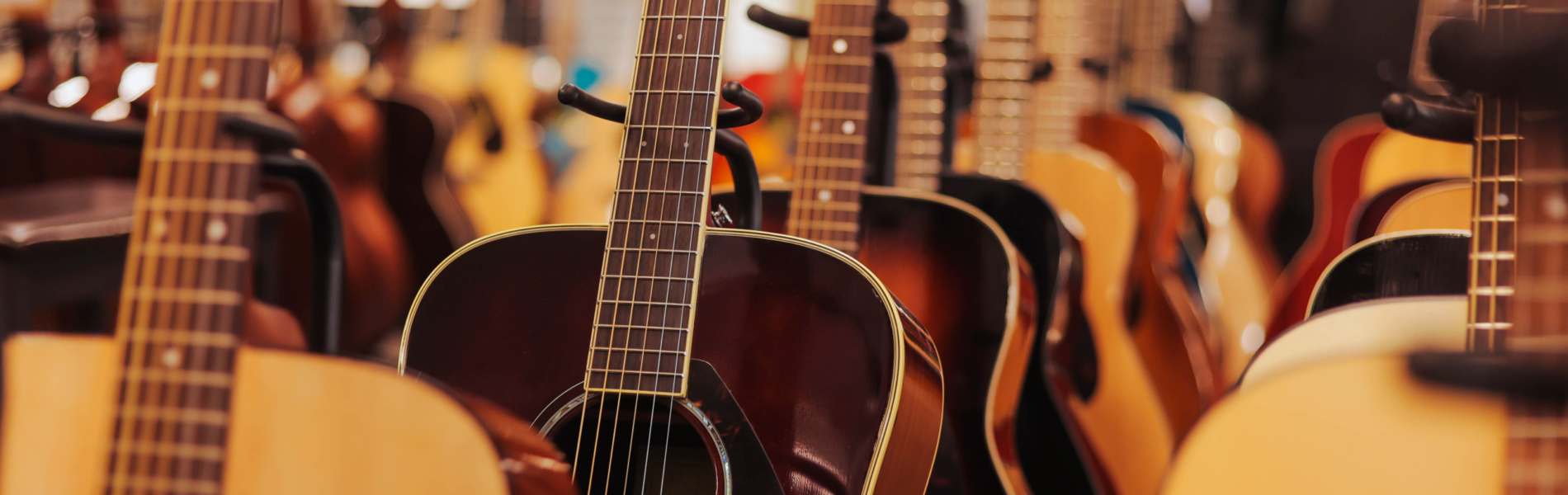 Many different acoustic guitars hanging on wall of music shop. Close up.